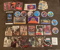 Top-down view of assorted trading cards including Spider-Man, Star Wars Galaxy, various round Marvel Shieldz cards, and others, along with unopened card packs.