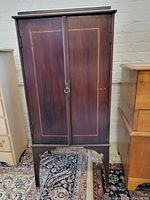 Front view of antique Stein's music cabinet with two doors and visible inlaid border on wood surface.
