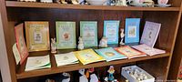 Books and figurines displayed on wooden shelf showing colorful children's books and ceramic figurines