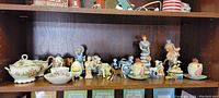 Shelf displaying figurines including ceramic animal figures, Goebel style figurines, and collector's egg coddlers.
