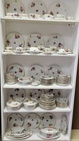 Shelves displaying the full collection of Victoria Maytime china including multiple plates, teacups, saucers and serving ware with floral pattern and gold accents.