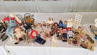 Table display of various vintage dolls, teddy bears, and doll chairs laid out.