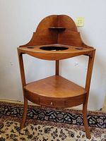 Front view of vintage wooden wash stand with one drawer, curved backsplash, and three cut-out holes in top surface.