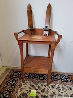 Front and angled view of the vintage wooden washstand with two wooden wall sconce candle holders placed on top.