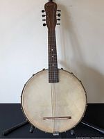 Front view of the entire banjo showing the detached back and full neck with tuning pegs.
