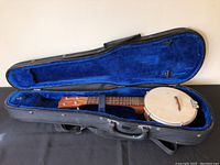 Banjo ukulele inside open blue velvet-lined violin case