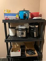Overall view of kitchen appliances and tools on shelving including air fryer, Instant Pot, rice cooker, scale, mixing bowls, and accessories