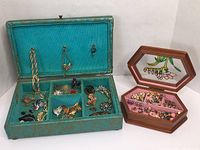 Two jewelry boxes with costume jewelry contents, showing brooches, pins, and earrings organized in compartments.