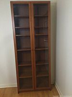 Full front view of IKEA wooden bookshelf with two glass doors closed showing overall condition and design