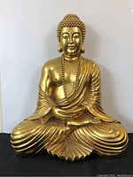 Front view of gold painted Buddha statue, seated in meditation with a chain necklace, showing surface wear.