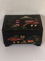 Front and top view of black lacquered wooden Japanese jewelry box with painted Mount Fuji, pagodas, and trees.