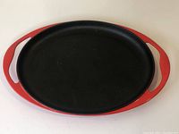 Top-down view of the skillet showing the oval cooking surface and red enamel handles.