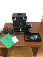 Machine, case, foot pedal, power cord, accessories tray and manuals on table