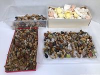 Overview of four trays and boxes filled with hundreds of small glazed ceramic figurines in various shapes