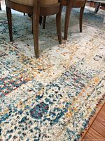 Close-up view of the multicolor patterned area rug under furniture, showing texture and wear.