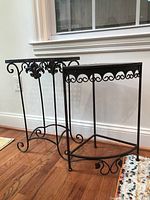 Two metal tables side by side showing overall shapes and decorative scrollwork