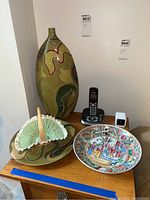 Photo showing all four items: tall decorative ceramic vase, matching plate, ceramic basket with handle, and colorful Asian-style porcelain plate.