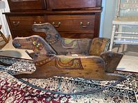 Side view of the wooden horse rocker showing hand painted facial and saddle details, and the rocker curved base.