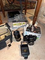 Photo showing Nintendo Wii console, Wii controllers, sensor bar, Wii Fit Plus game, other Wii games, Konica FP-1 camera with zoom lens, external flash, and camera case.