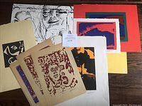 Overview photo showing nine assorted unframed Watson Winnison prints stacked with visible variety in styles and colors.