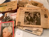Overview of newspapers and magazines spread on a surface showing vintage pages, front-page headlines and covers