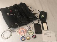 Photo shows women's black dance shoes with laces, two iPod devices, a white charging cord, and assorted button pins arranged around a black soft fabric bag labeled 'Pontec'.