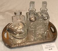Full view of the glass bar set items arranged on the silver-plated tray showing decanters, ice bucket, tongs, and decanter tags.
