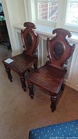 Photo of the pair of antique Victorian wooden hall chairs side by side showing overall condition and design.