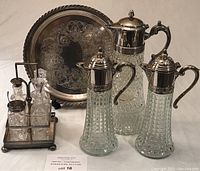Photo showcasing full lot including 3 decanter carafes, round tray, and condiment set in caddy