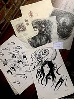 Photo shows multiple unframed black and white art prints placed on the floor, including portraits and Indigenous themes.