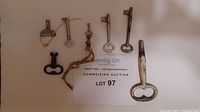 Full collection of 7 skeleton keys shown with auction lot card for scale.