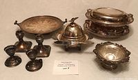 Overview of all silver-plated items in the lot showing serving dishes, platter, candlesticks, knife, and bowl
