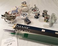 Full lot view showing all small assorted pieces including two teapots, sake cups, egg cups, collectible teaspoons, and Dansk candlesticks in boxes.