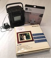 Yorx cassette tape player, Umbra LED photo display box, Polaroid digital photo frame box arranged on white surface