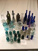 Group shot of all bottles and insulators arranged on white surface showing variety of colors and shapes