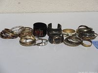 Lot of 27 vintage metal bracelets including gold filled, metal cuffs, rhinestones, Morson wind watch with silver inlay bracelet band. Items are pre-owned and arranged together in a group.