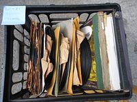 Top view of crate filled with 78 RPM vinyl records in paper sleeves and some outer covers.