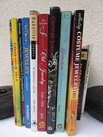 Photo of ten reference books standing upright showing their spine titles related to costume jewelry, glassware, vintage toys, and collectibles.