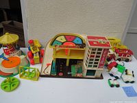 Photo of entire lot showing garage playset, merry-go-round record player, wooden pull toy, buses, smaller vehicles