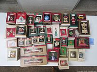 Overhead view of 36 boxed Christmas ornaments from Hallmark and Campbell's Soup arranged on white surface.