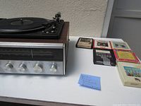 Photo of JC Penney all-in-one player showing left side with record turntable and control knobs and six 8-track tapes on the right