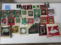 Full layout of 30 Hallmark ornaments in original packaging, including a visible locomotive ornament, Star Trek miniatures, and numerous flat ornaments