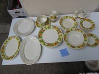 23 pieces of Metlox Poppytrail dinnerware arranged on table including platters, plates, bowls, cream pitcher, salt shaker, and gravy boat.