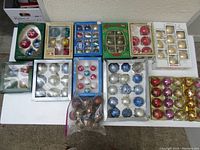 Photo of multiple boxed sets of ball ornaments in various colors and some loose ornaments in plastic bag.
