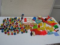 Full lot display showing 69 Little People figures, accessories, and vehicles on a white surface outdoors against light background.