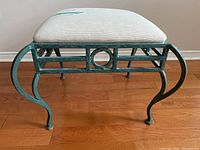 Front angle showing the green metal frame with curved leg design and circular detail, topped with white upholstered seat.