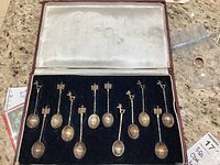 Twelve handcrafted 900 silver demitasse spoons in original fitted case, showing twisted handles and decorative bird and eagle finials.