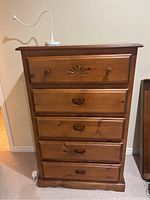 Front view of wood dresser with five drawers and small white LED lamp on top
