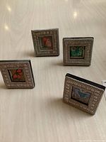 Four small square framed butterfly artworks arranged on table, showing front views of frames and butterfly illustrations.