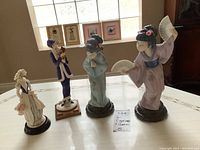 Front view of four figurines on table including two Lladro geisha and two Armani resin figurines.